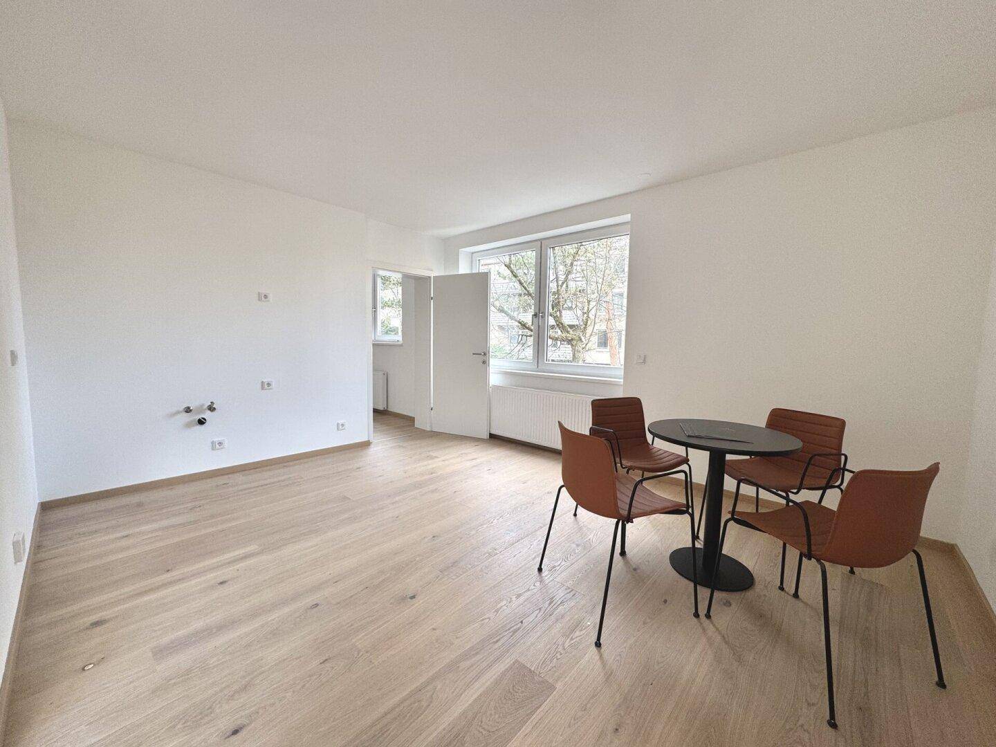 Geräumiger Bereich mit Parkettboden, Esstisch und Stühlen, ideal für offenes Wohnen.