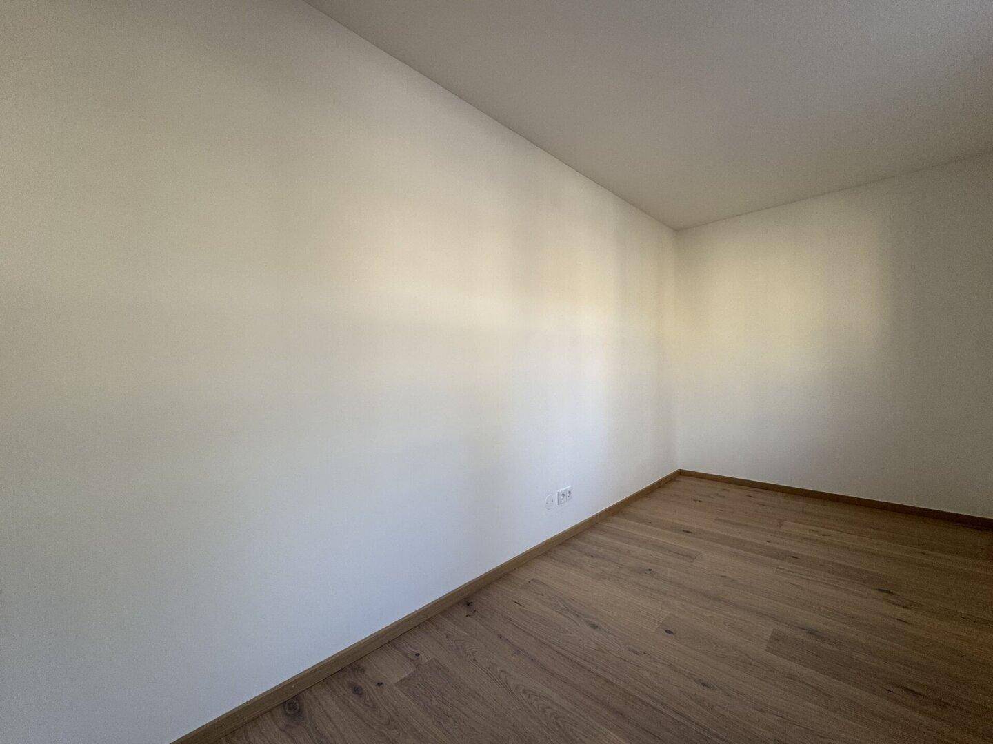 Ruhiges Zimmer mit Parkettboden und weißen Wänden, ideal als Schlaf- oder Arbeitszimmer.