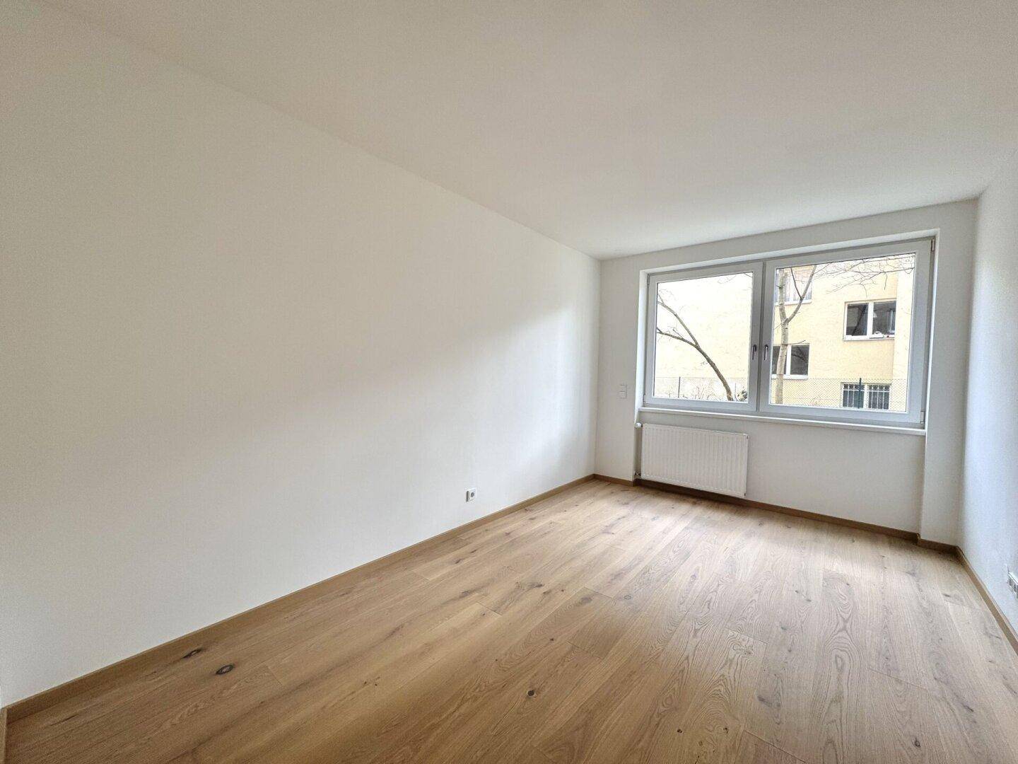Helles Zimmer mit Parkettboden und weißen Wänden, bereit zur individuellen Einrichtung.