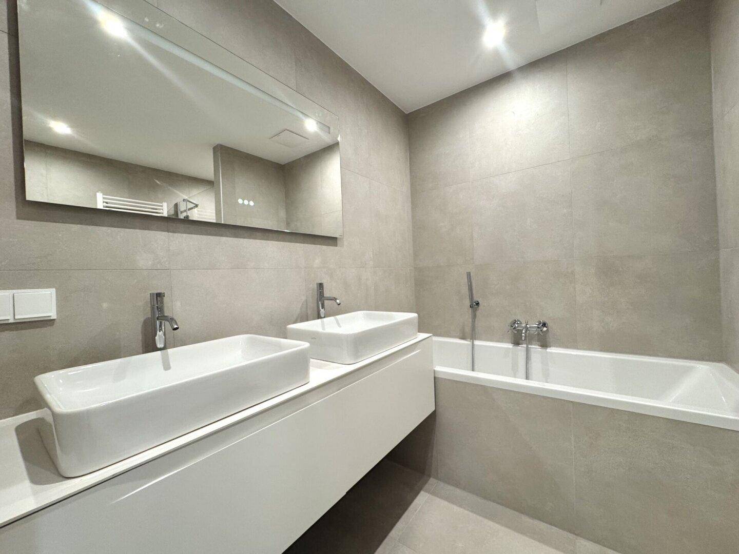 Modernes Badezimmer mit Doppelwaschbecken, Badewanne und großem Spiegel.