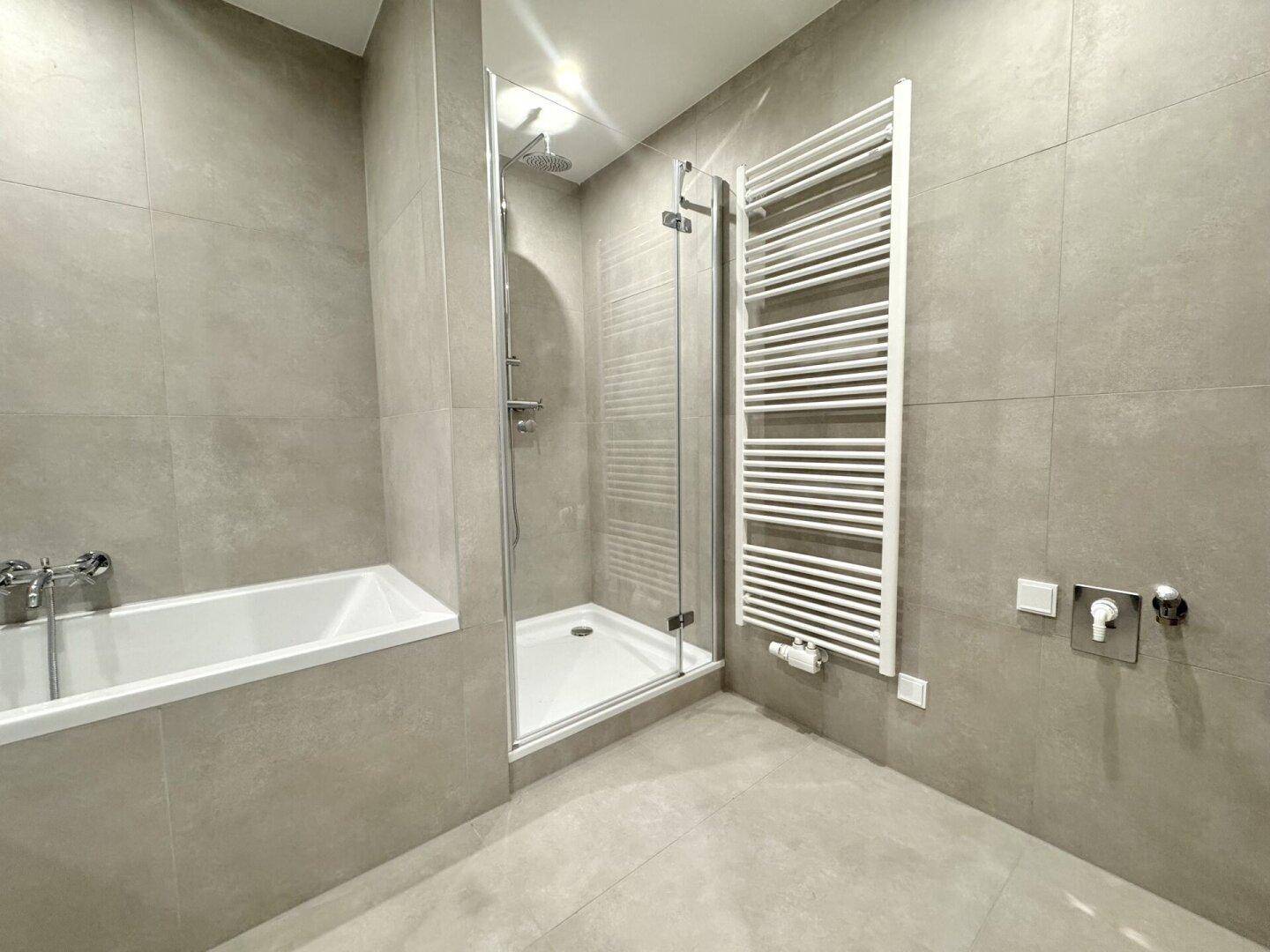 Modernes Badezimmer mit Badewanne, Duschkabine und beheiztem Handtuchhalter.