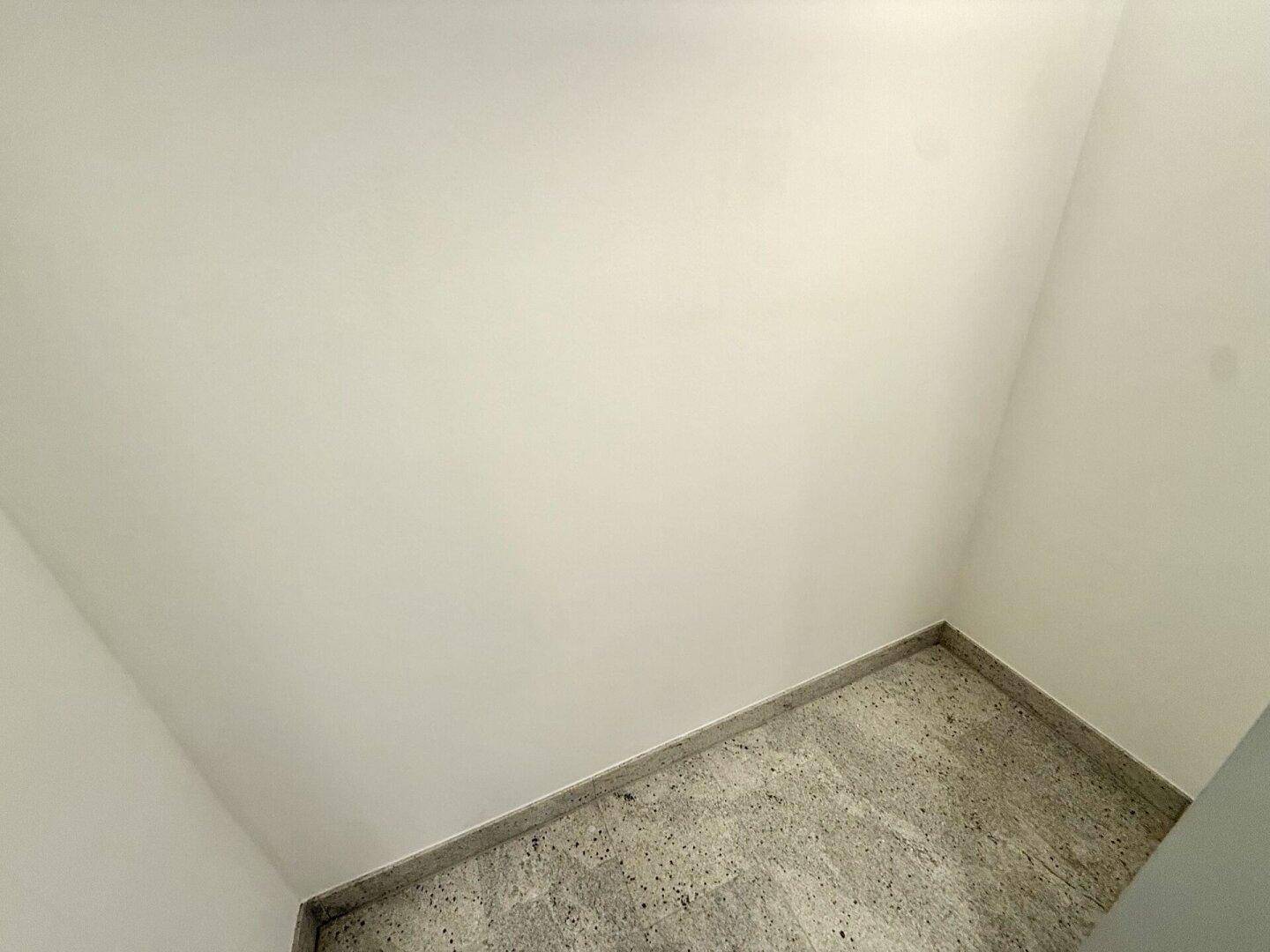 Deckenansicht und Ecke eines Flurs mit hellem Fliesenboden.