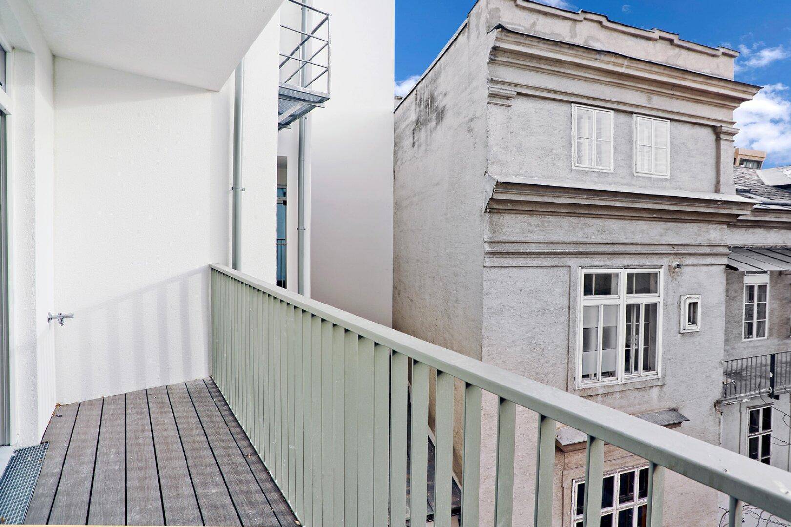 Balkon mit moderner Brüstung und Blick auf die historische Architektur der Nachbargebäude.