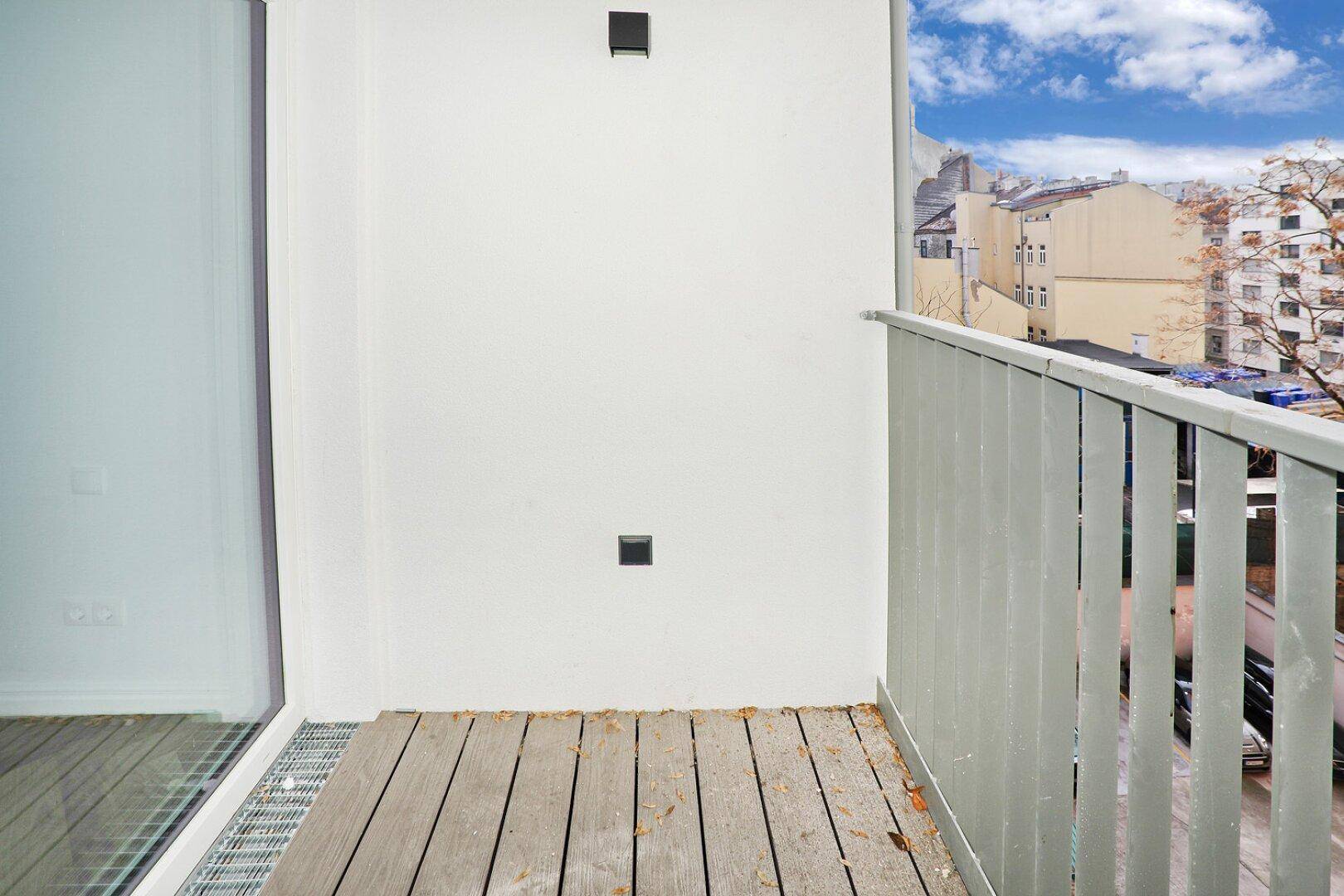 Schmaler Balkon mit Holzplanken und Metallgeländer, ideal für frische Luft.