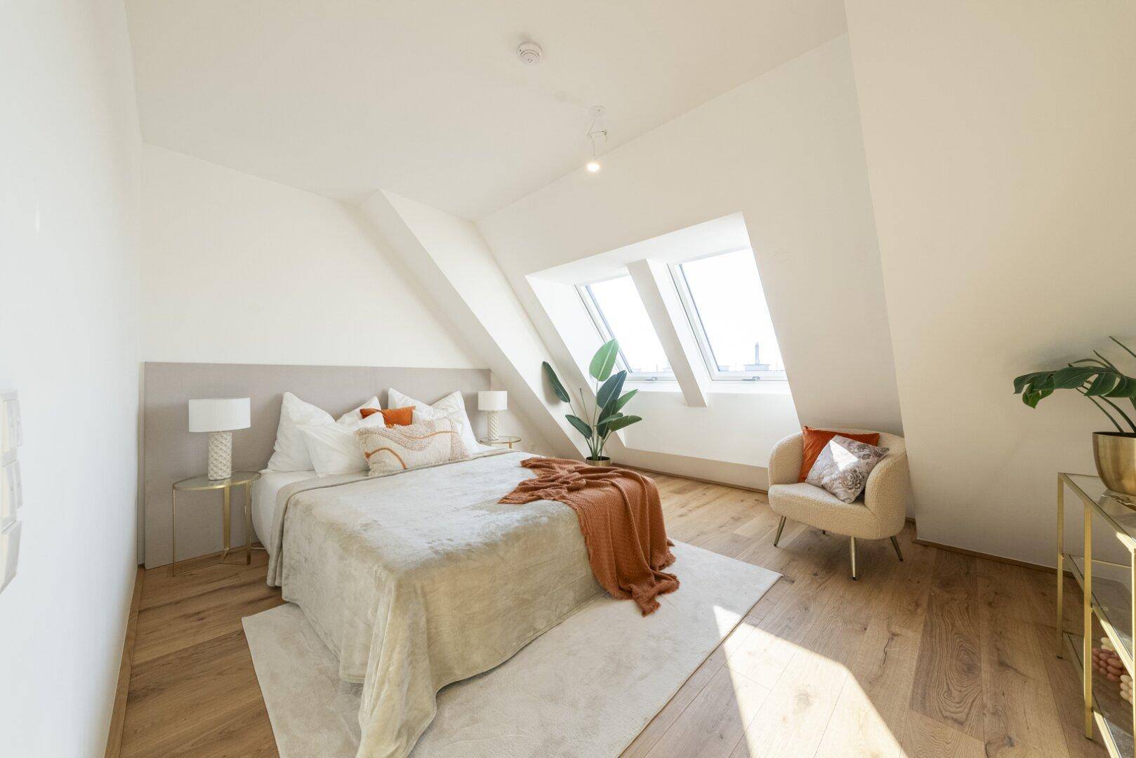 Helles Schlafzimmer im Dachgeschoss mit Holzboden, Dachfenstern und modernem Doppelbett.