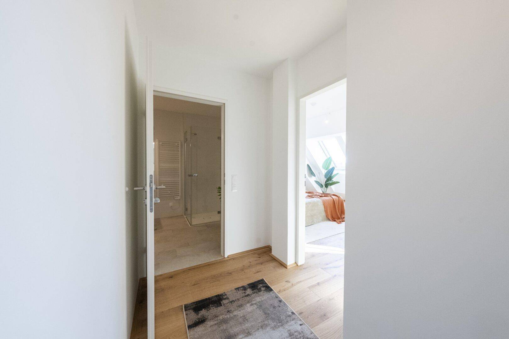 Heller Flur mit Holzboden, der zu einem Badezimmer und einem weiteren Zimmer führt.