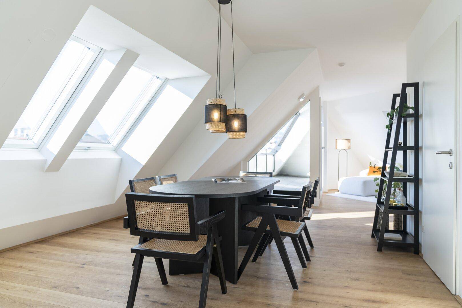 Geräumiger Essbereich im Dachgeschoss mit Holzboden, stilvollem Esstisch und viel Tageslicht.