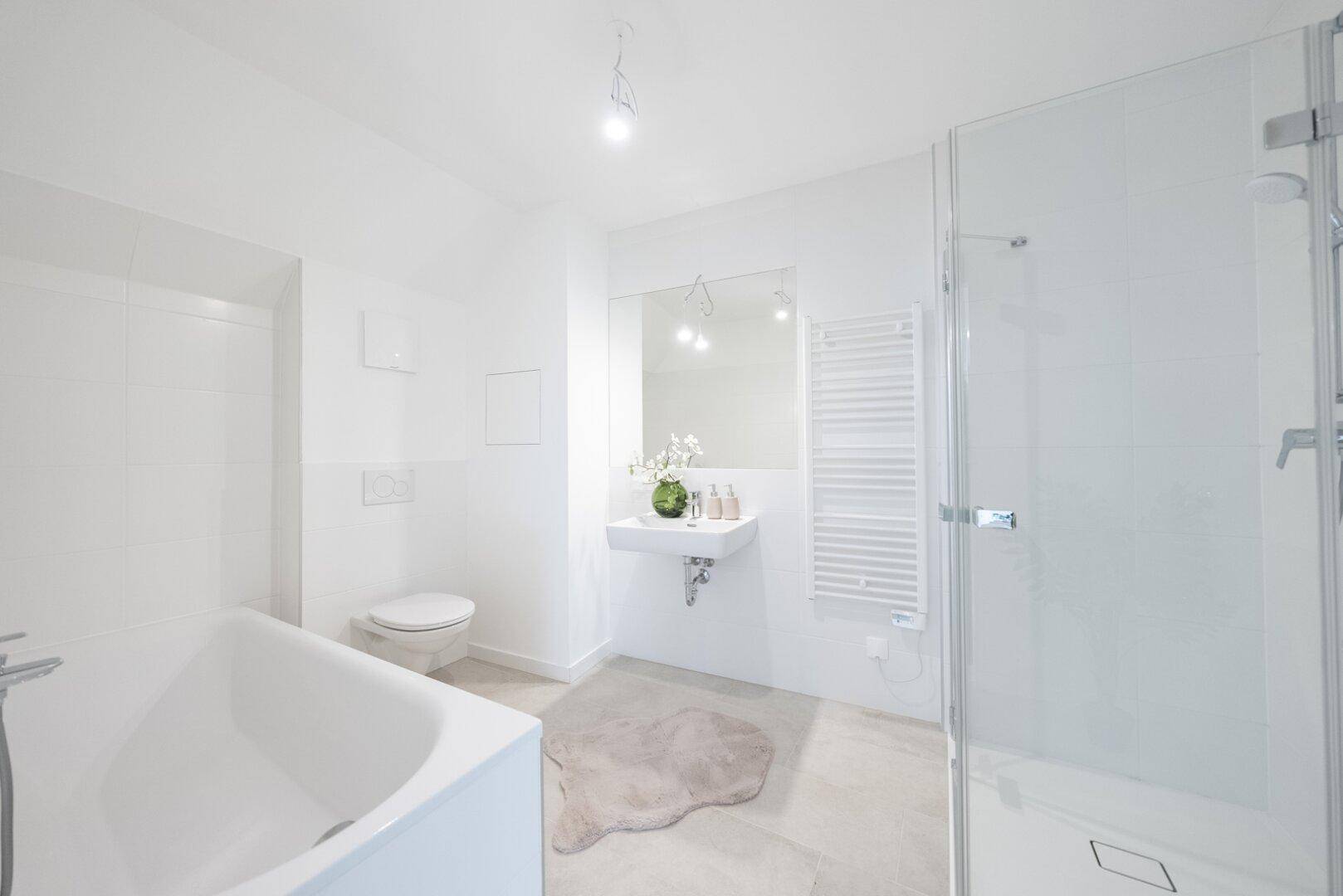 Helles Badezimmer mit Badewanne, Duschkabine, Waschbecken und modernen Fliesen.