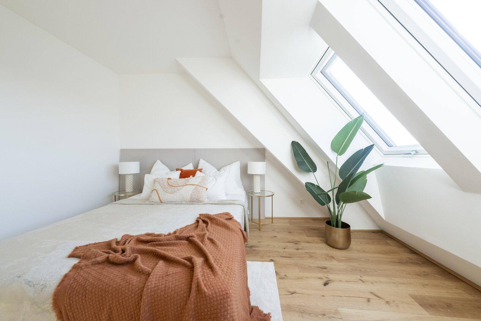 Gemütliches Schlafzimmer im Dachgeschoss mit Holzboden, Dachfenstern und bequemer Einrichtung.