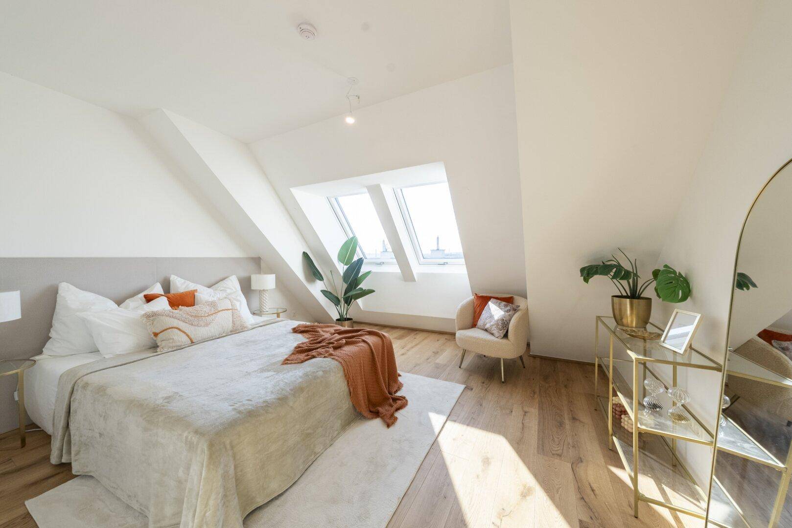 Helles Schlafzimmer im Dachgeschoss mit Holzboden, Dachfenstern und stilvoller Dekoration.