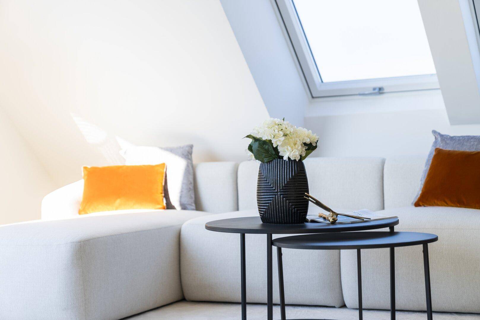 Detailansicht des Sofas und der Beistelltische im hellen Wohnbereich mit moderner Dekoration.