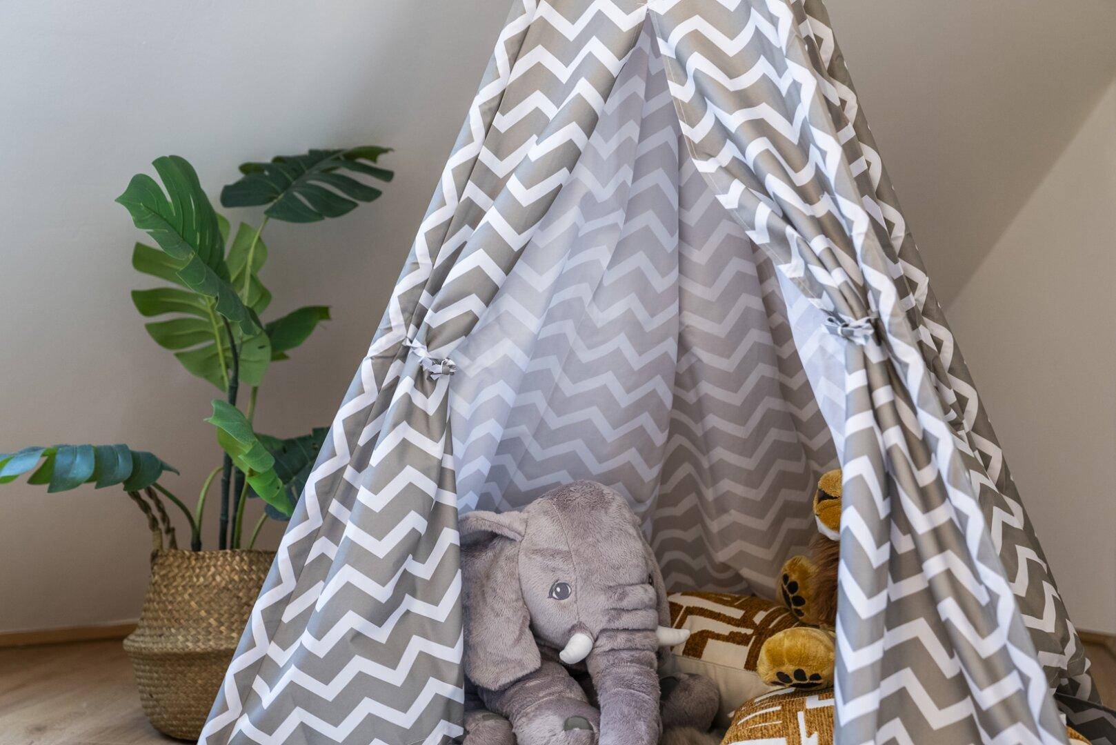 Gemütliches Kinderzimmer mit einem Spielzelt und Stofftieren unter einer Dachschräge.