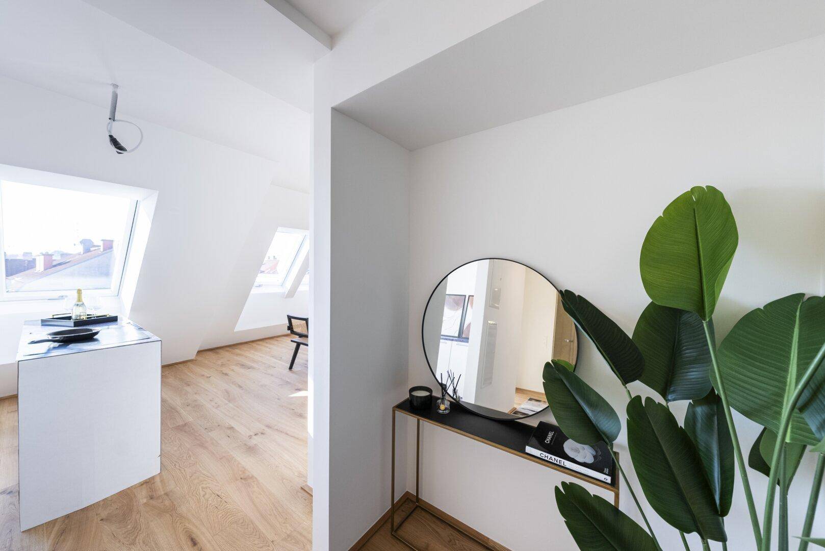 Moderner Eingangsbereich mit Spiegel und Blick in den offenen Wohnbereich mit Dachfenstern.
