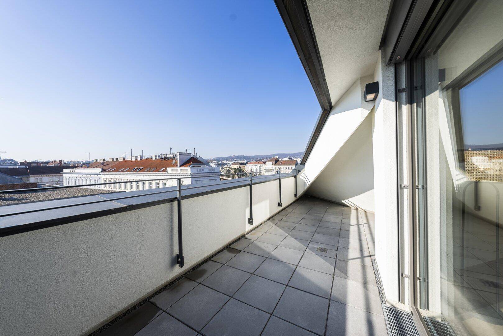 Weitläufige Dachterrasse mit Fliesenboden und Panoramablick auf die umliegende Stadtlandschaft.