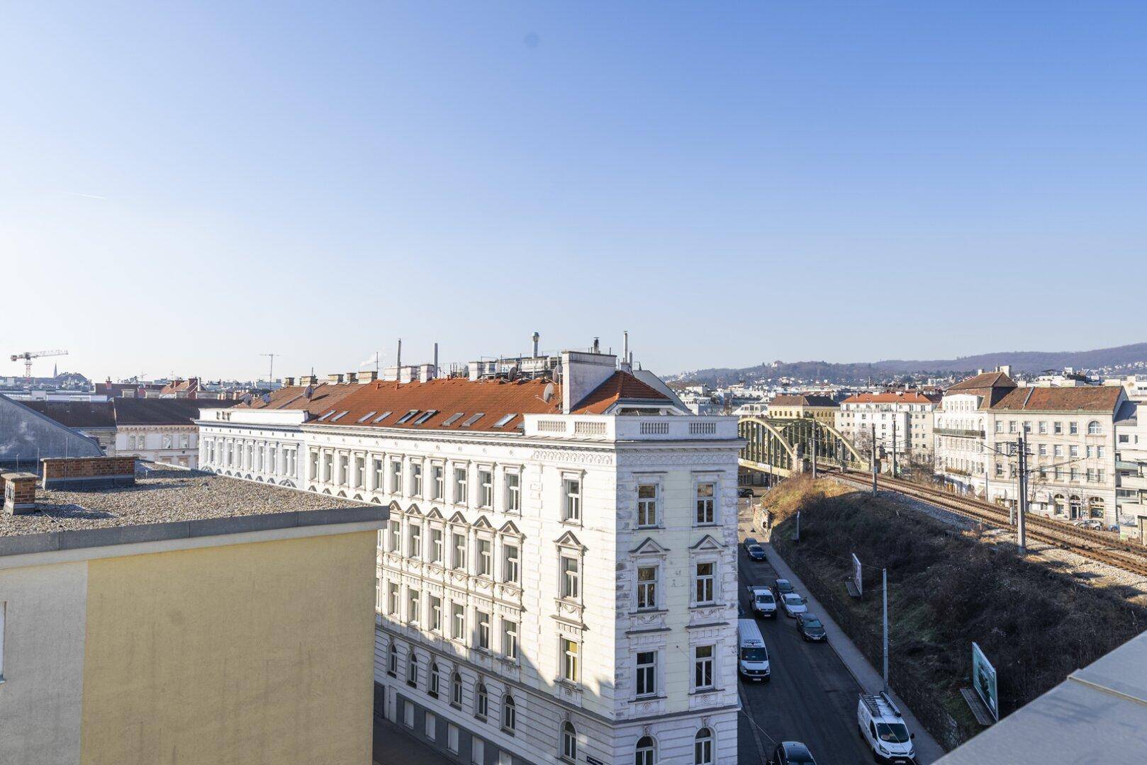 Panoramablick über die Stadt mit historischen Gebäuden und einer Eisenbahnbrücke im Hintergrund.