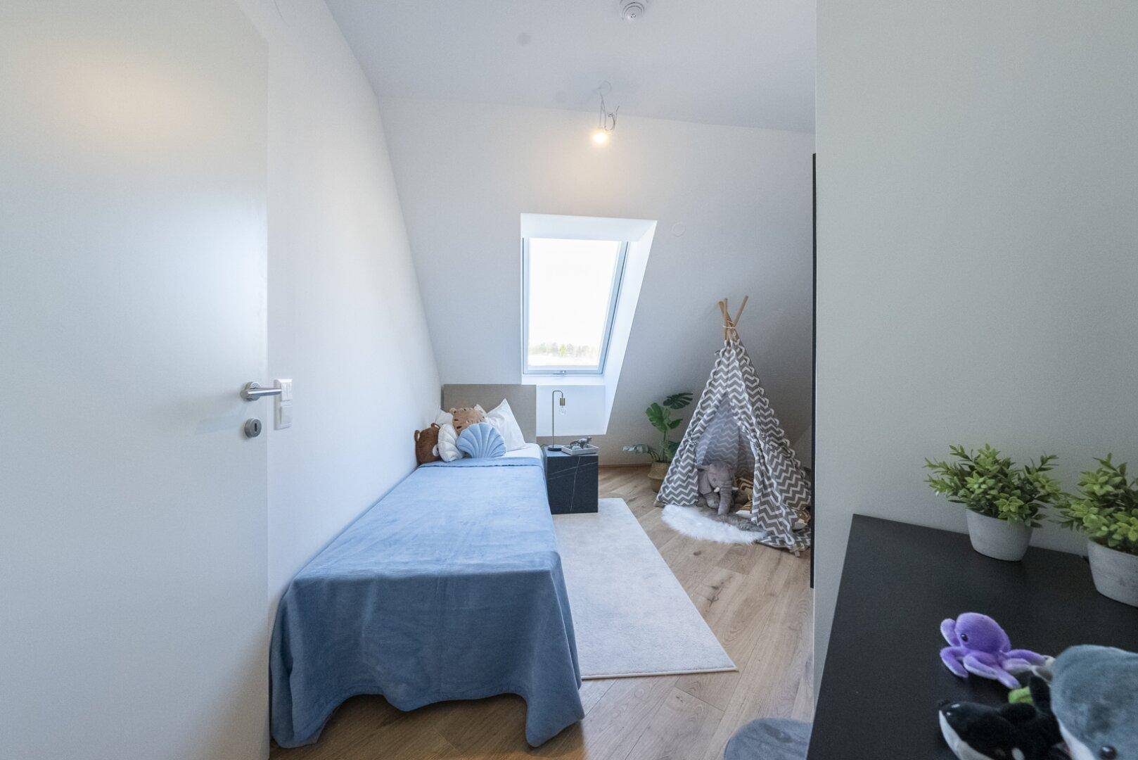 Modernes Kinderzimmer im Dachgeschoss mit Holzboden, Spielzelt und viel Tageslicht.