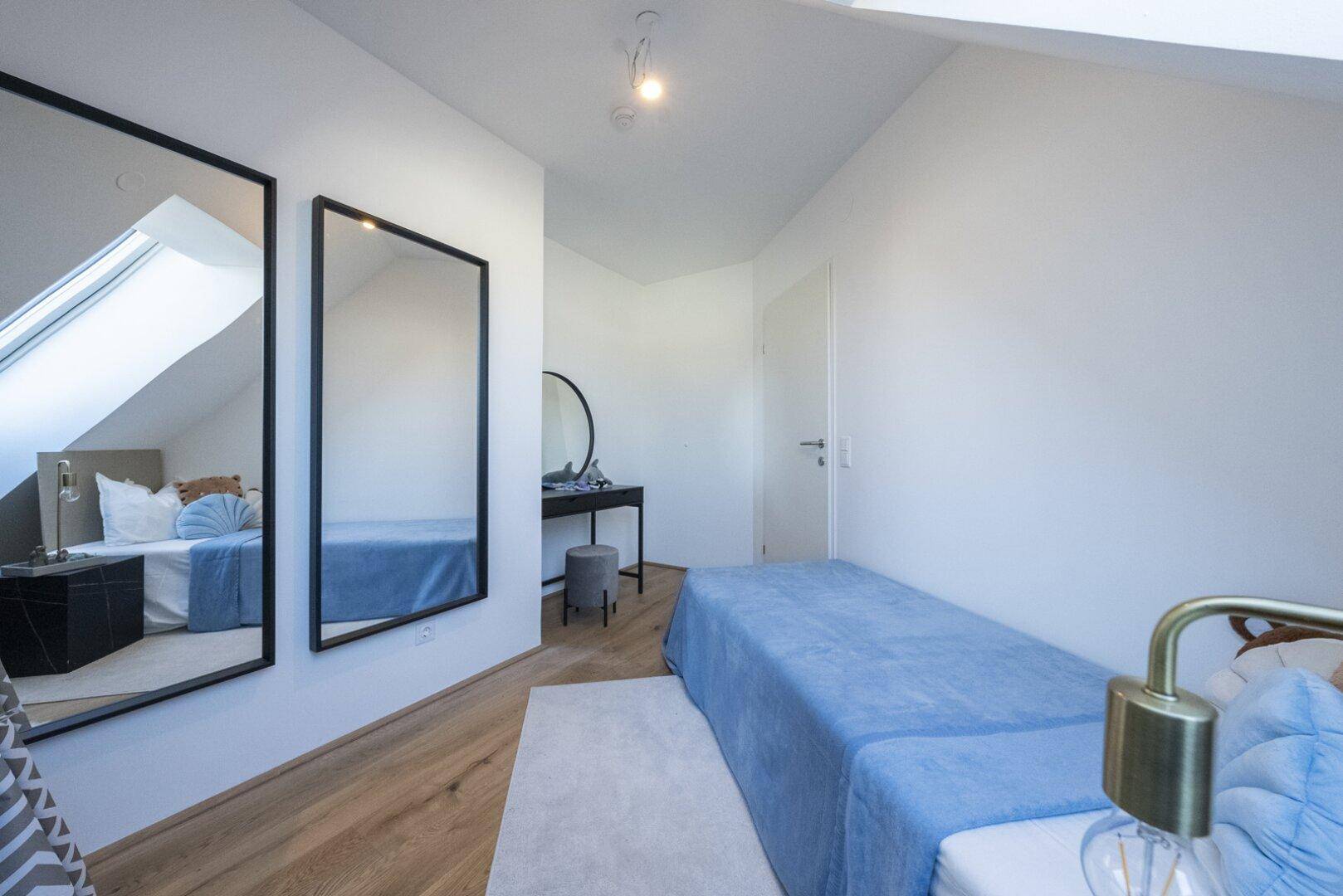 Gemütliches Schlafzimmer mit Holzboden, zwei großen Spiegeln und einem Dachfenster.