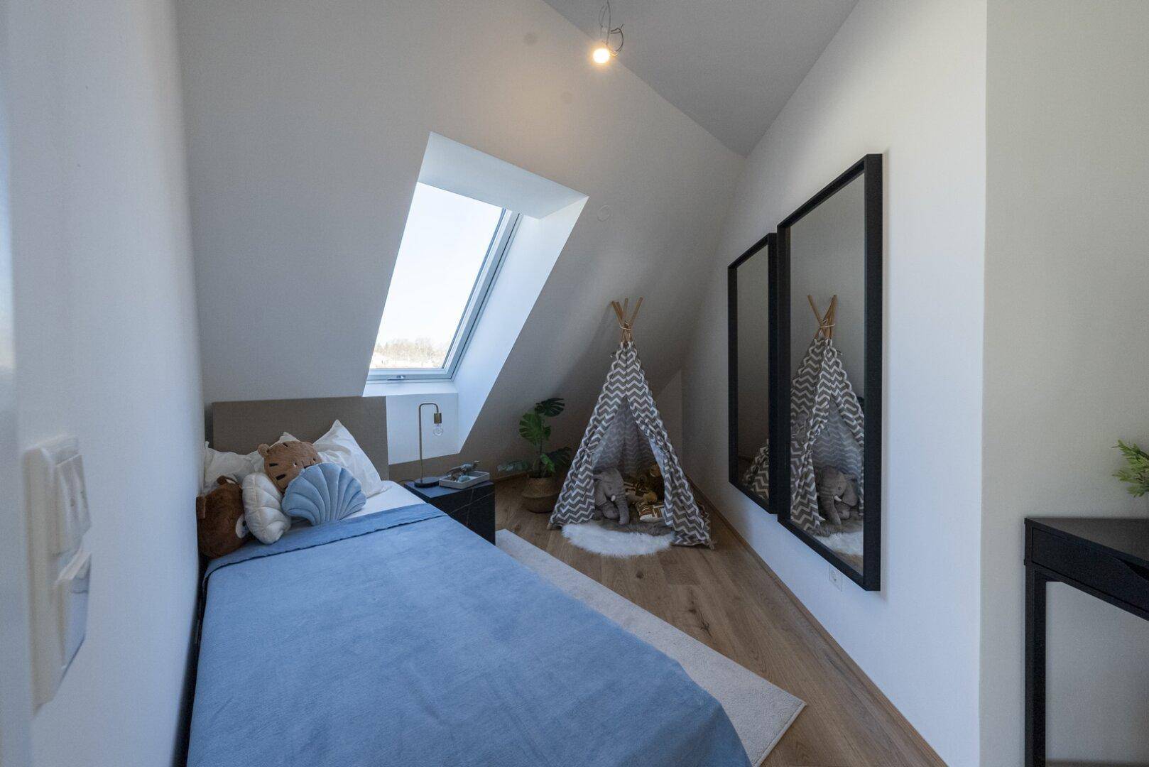 Gemütliches Kinderzimmer mit Einzelbett, Spielzelt und Dachfenster unter der Schräge.