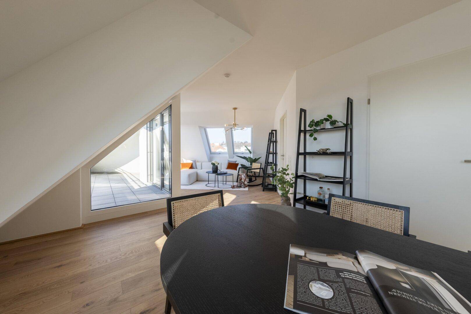 Offener Wohn- und Essbereich mit Zugang zur Terrasse und großen Fenstern.