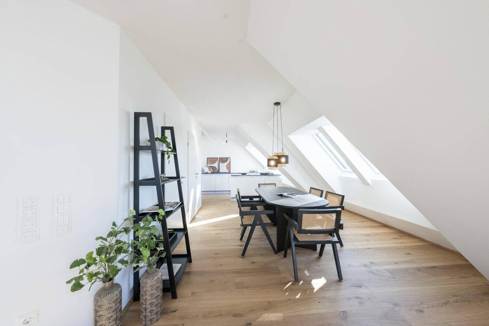 Offener Wohn- und Essbereich im Dachgeschoss mit Holzboden und moderner Einrichtung.