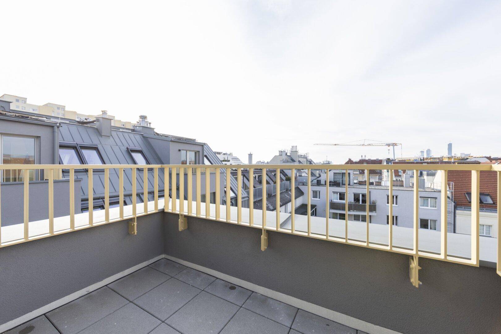 Geräumige Dachterrasse mit Fliesenboden, modernem Geländer und weitem Stadtblick.