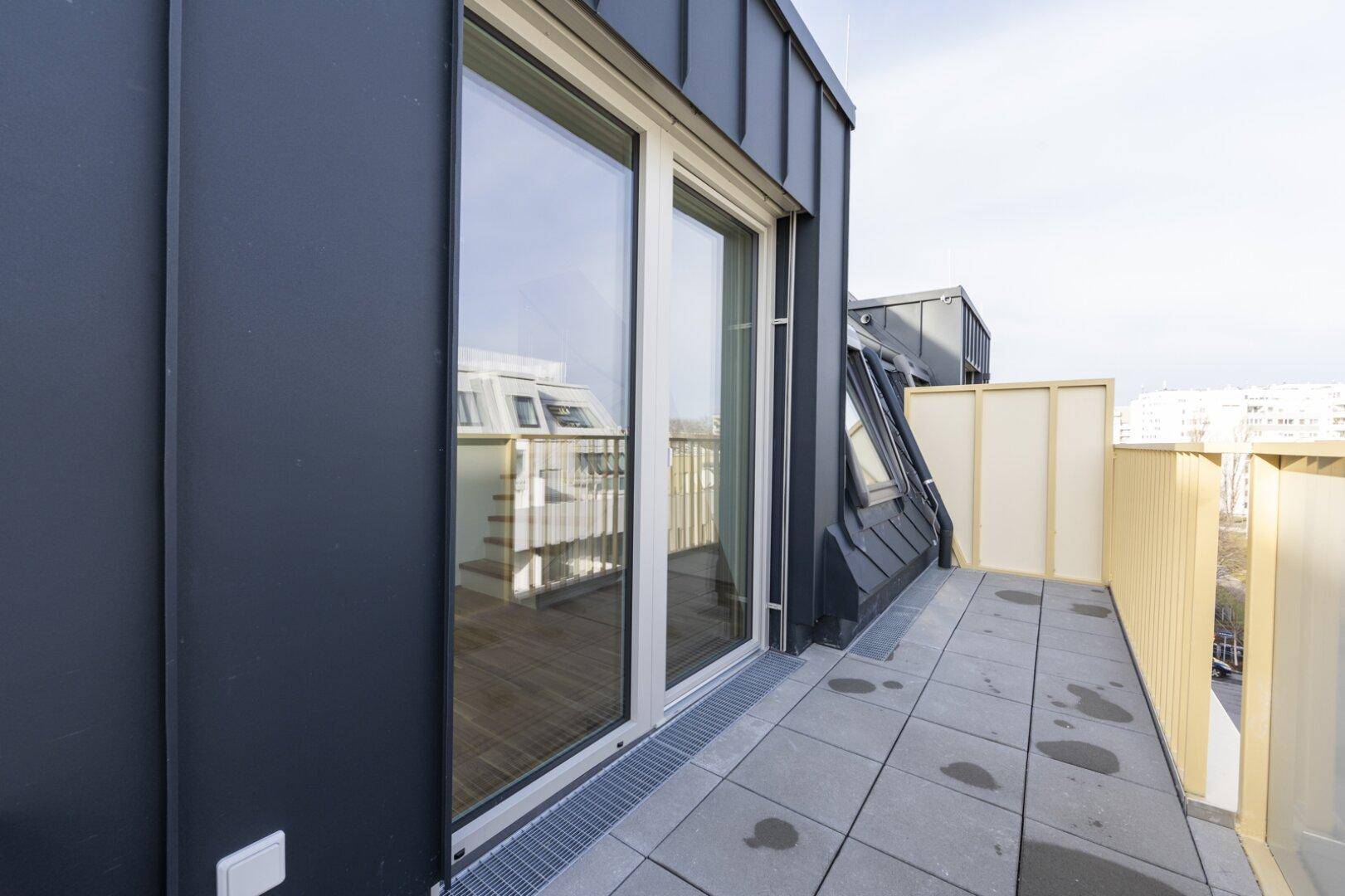 Balkonzugang mit großen Fenstern und modernem Geländer, Teil einer Dachgeschosswohnung.