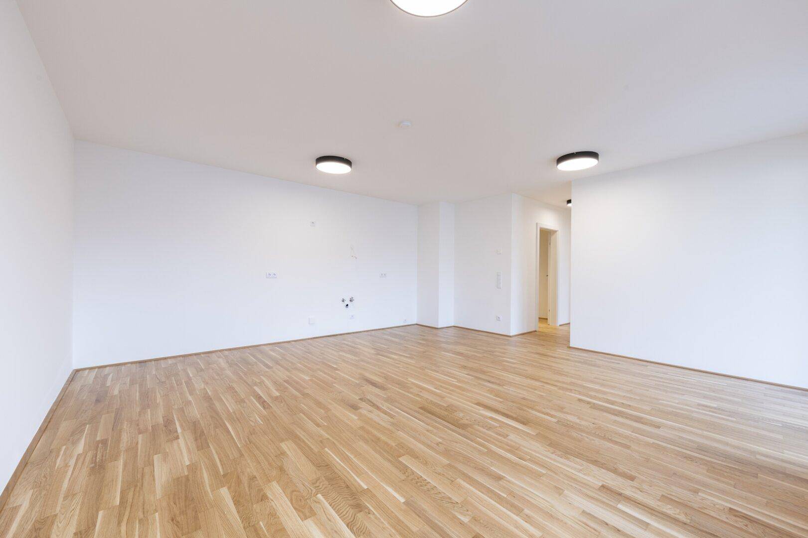 Geräumiges, leeres Zimmer mit Parkettboden und weißen Wänden, bereit zur individuellen Gestaltung.