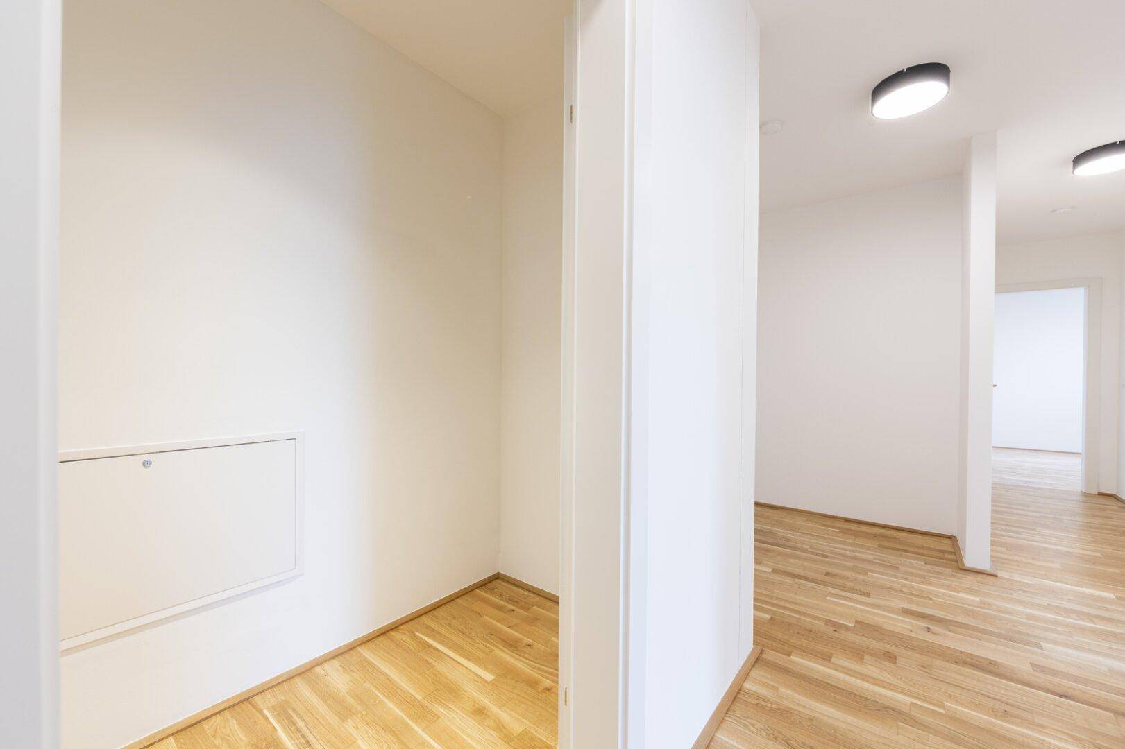 Kleiner Abstellraum mit Parkettboden und einer Wartungsklappe, ideal für zusätzlichen Stauraum.