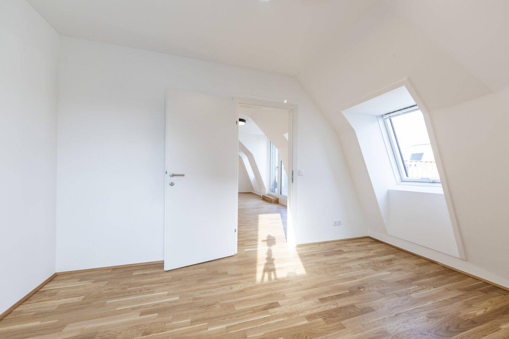 Helles Schlafzimmer im Dachgeschoss mit Parkettboden, Dachschräge und viel Tageslicht.