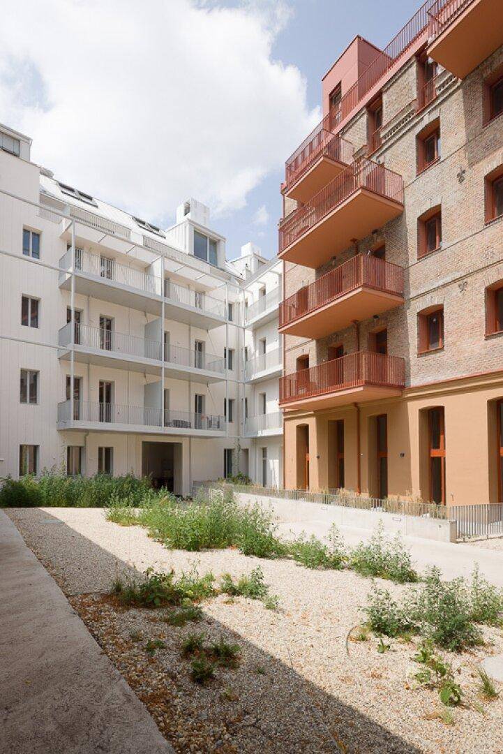 Innenhofansicht mit moderner weißer Fassade und angrenzender Backsteinfassade.