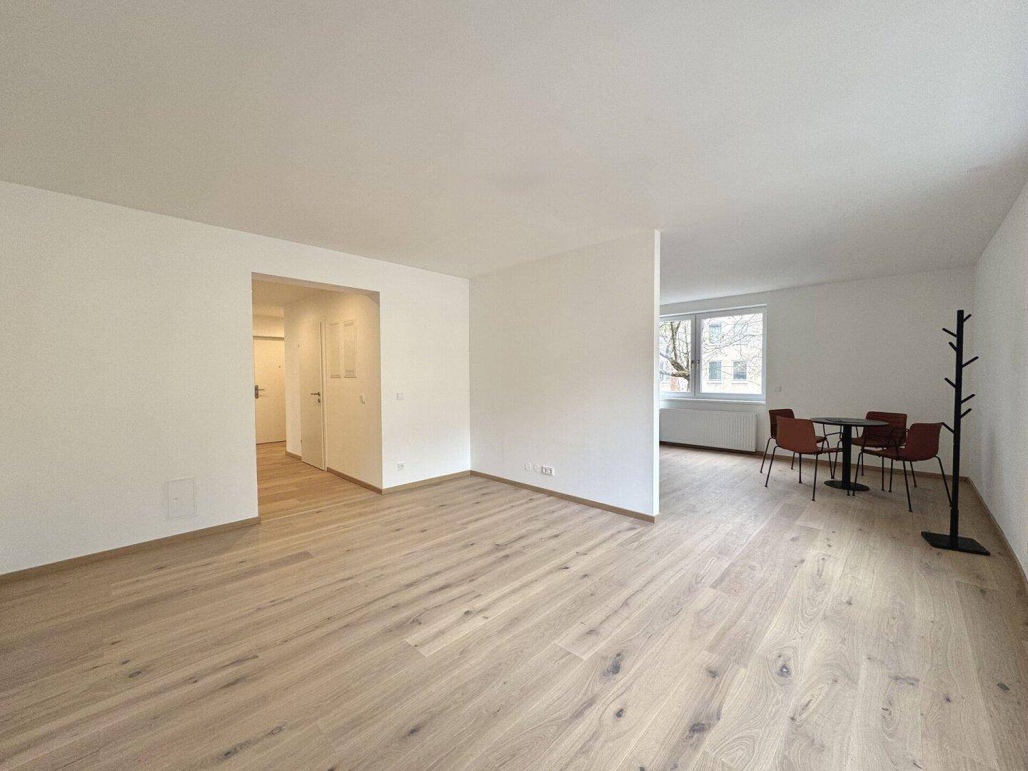 Offener Wohnbereich mit Parkettboden, Essplatz und Blick auf den Eingangsbereich.