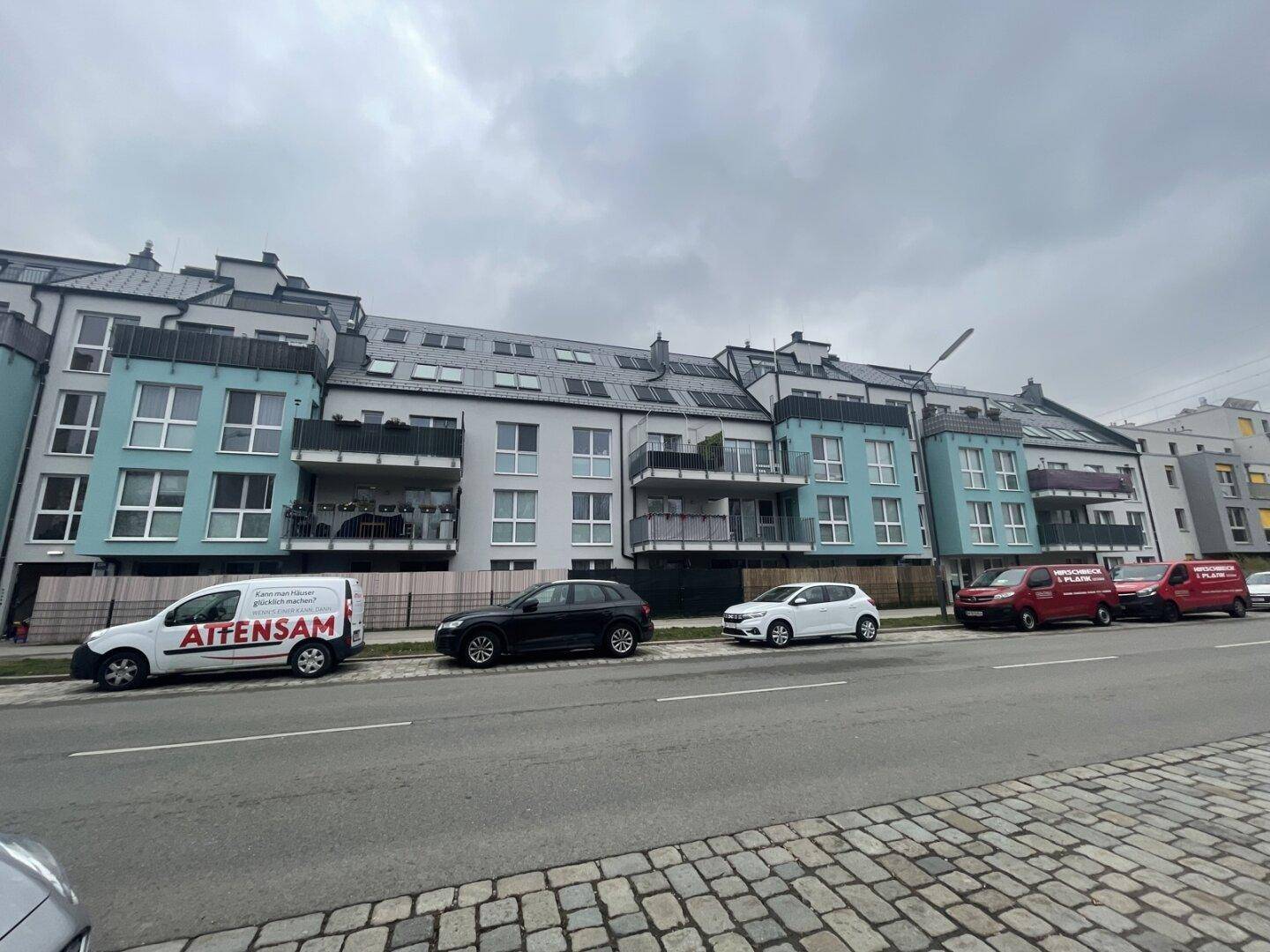 Moderne Wohngebäude mit farbigen Fassaden, Balkonen und Dachgauben entlang einer Straße.