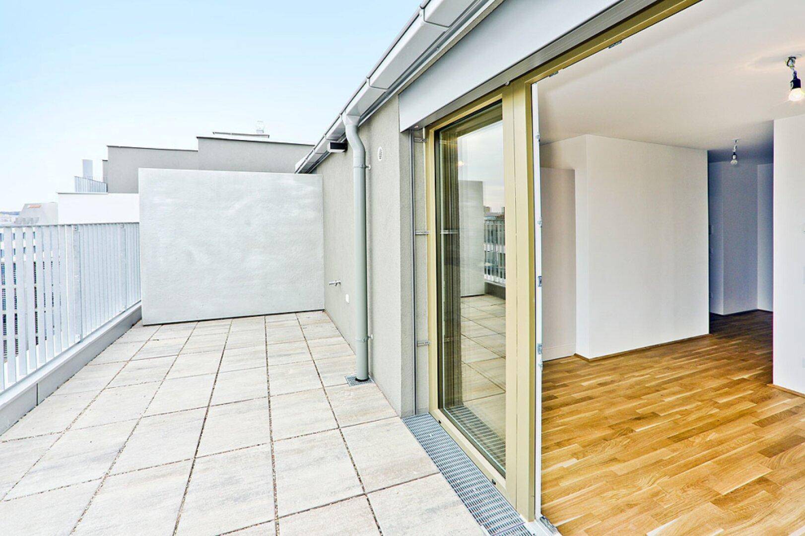 Geräumige Dachterrasse mit Fliesenboden und Blick auf die Umgebung, zugänglich vom Innenraum.