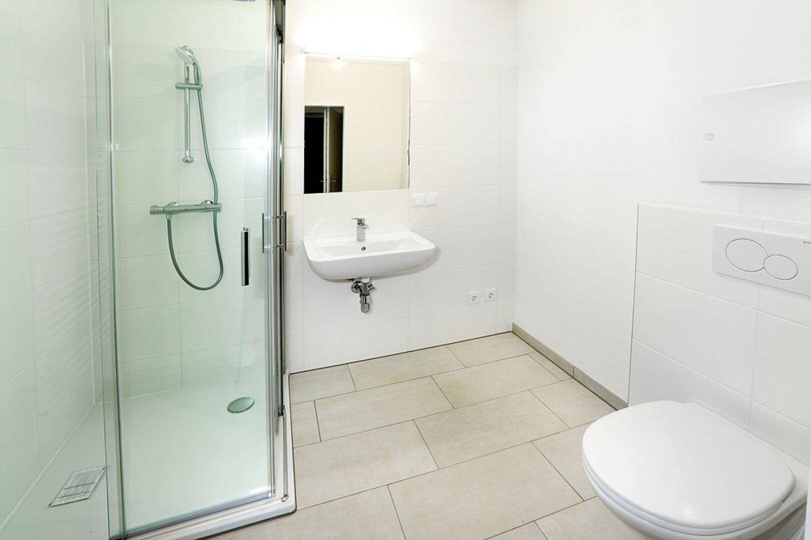 Helles Badezimmer mit Duschkabine, WC und Waschbecken.