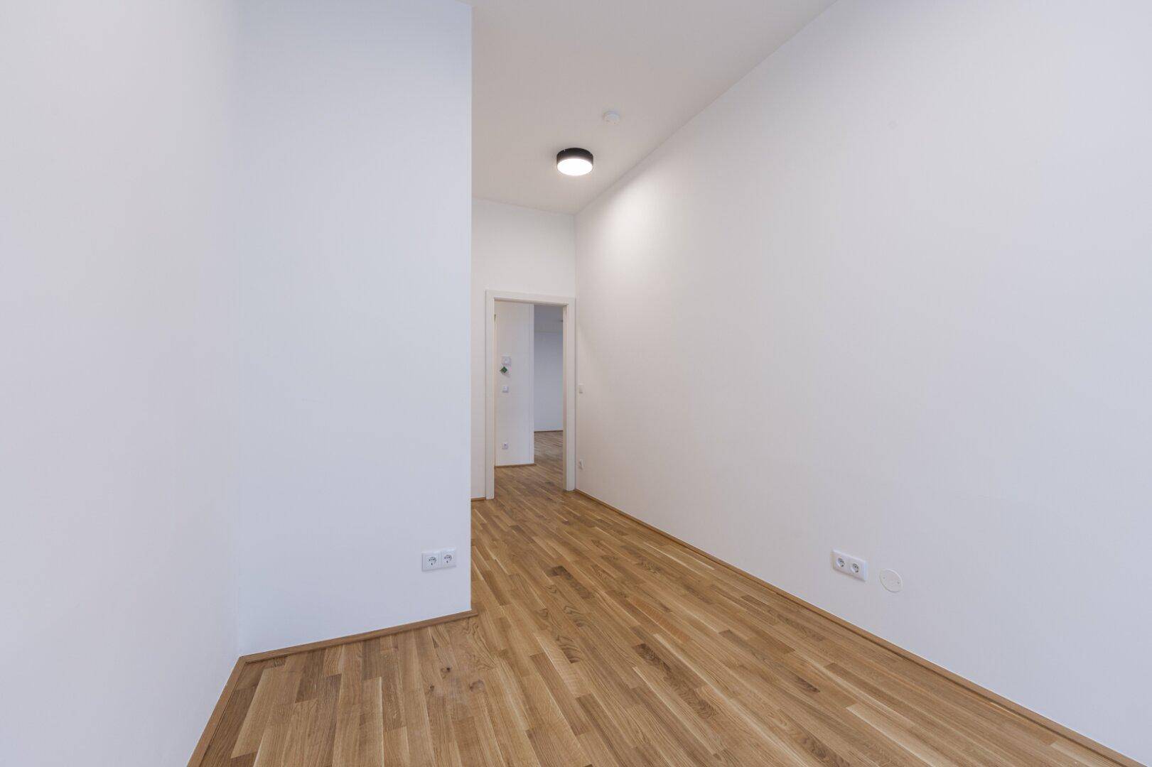 Leerer Raum mit Parkettboden und weißen Wänden, der vielseitig als Schlafzimmer oder Büro genutzt werden kann.