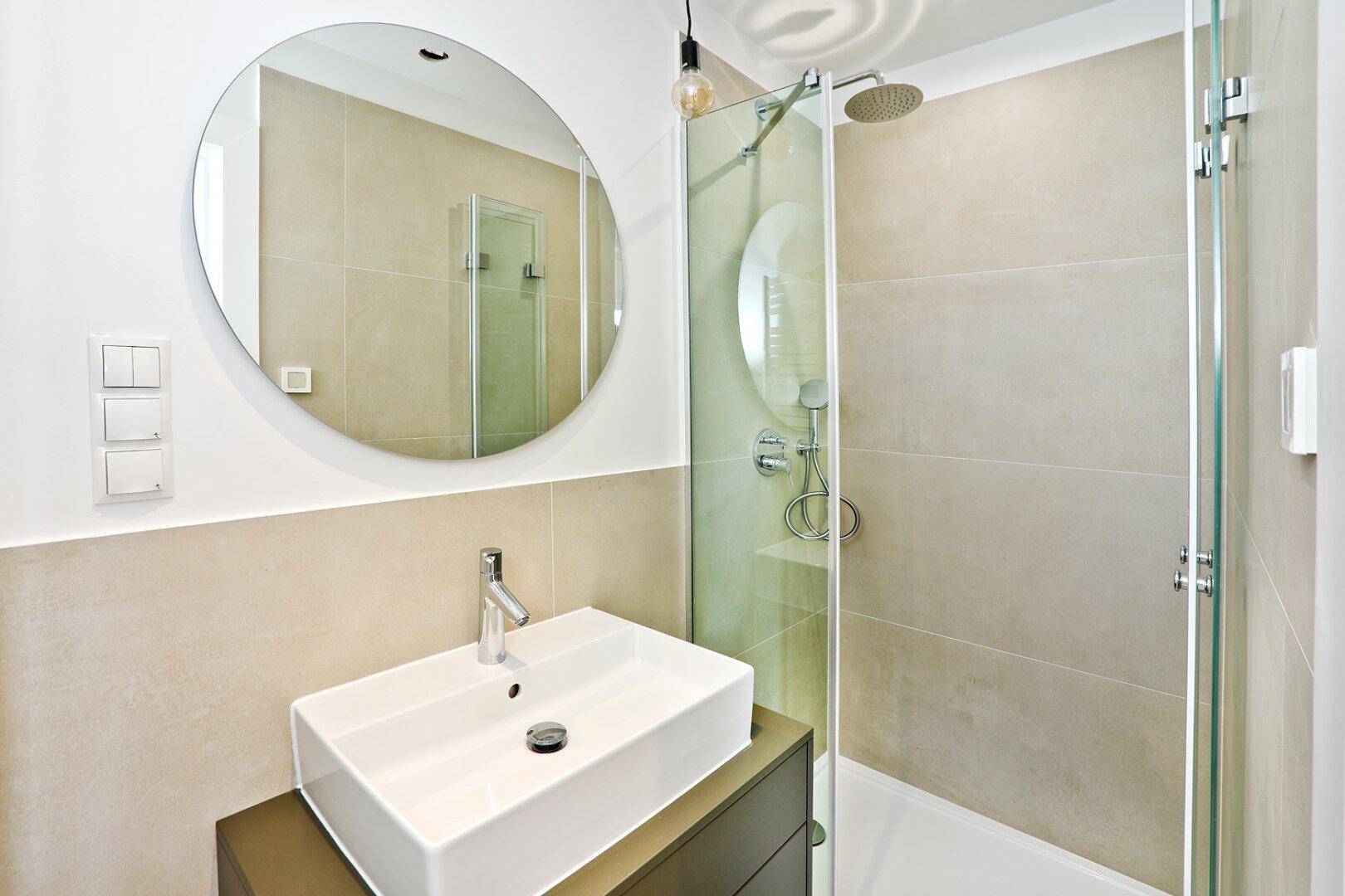 Modernes Badezimmer mit beigefarbenen Fliesen, Aufsatzwaschbecken und großer Dusche.