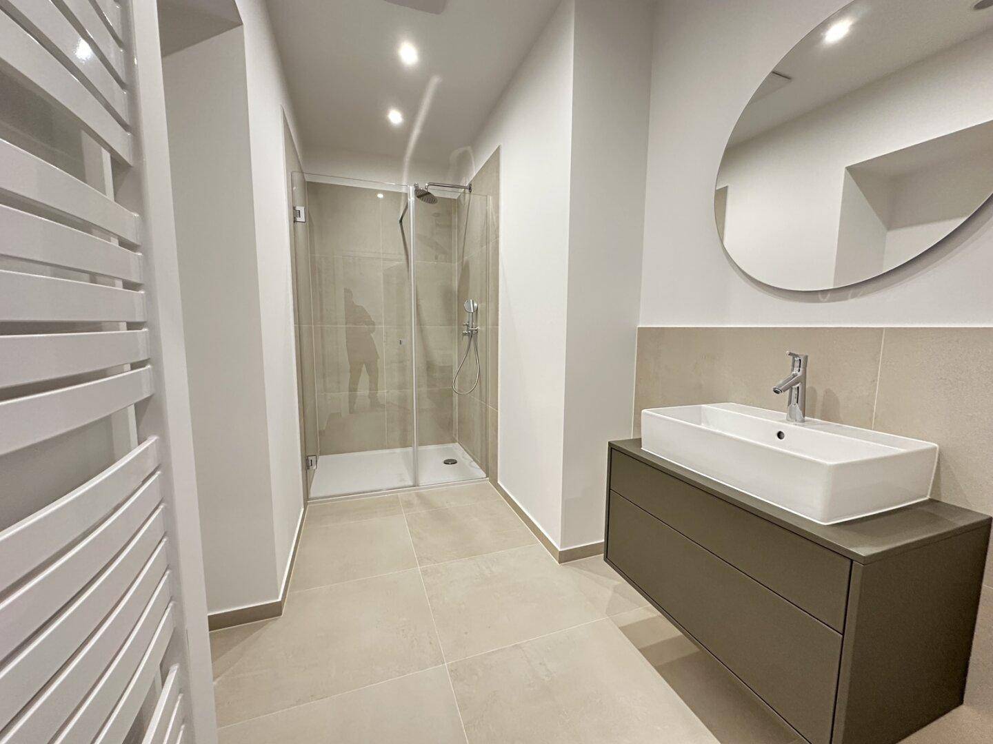 Modernes Badezimmer mit begehbarer Dusche, elegantem Waschtisch und praktischem beheiztem Handtuchhalter.