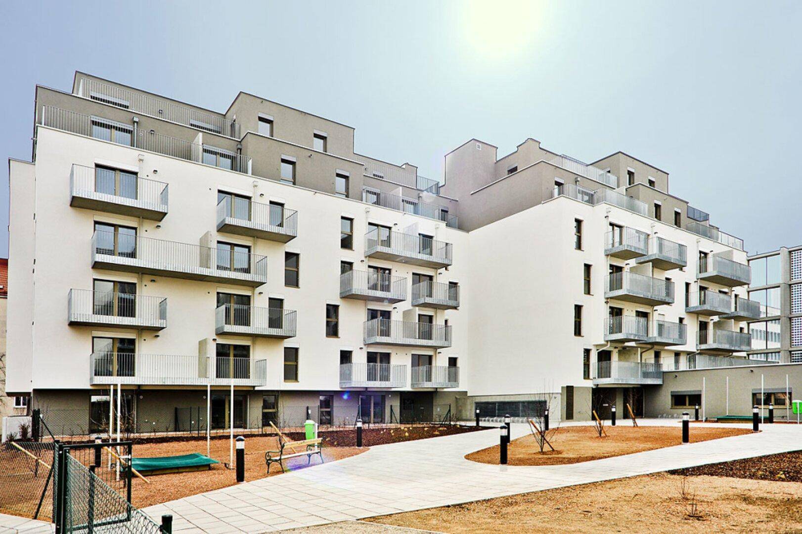 Neubau eines modernen Wohngebäudes mit Balkonen und einem Spielplatz im Außenbereich.