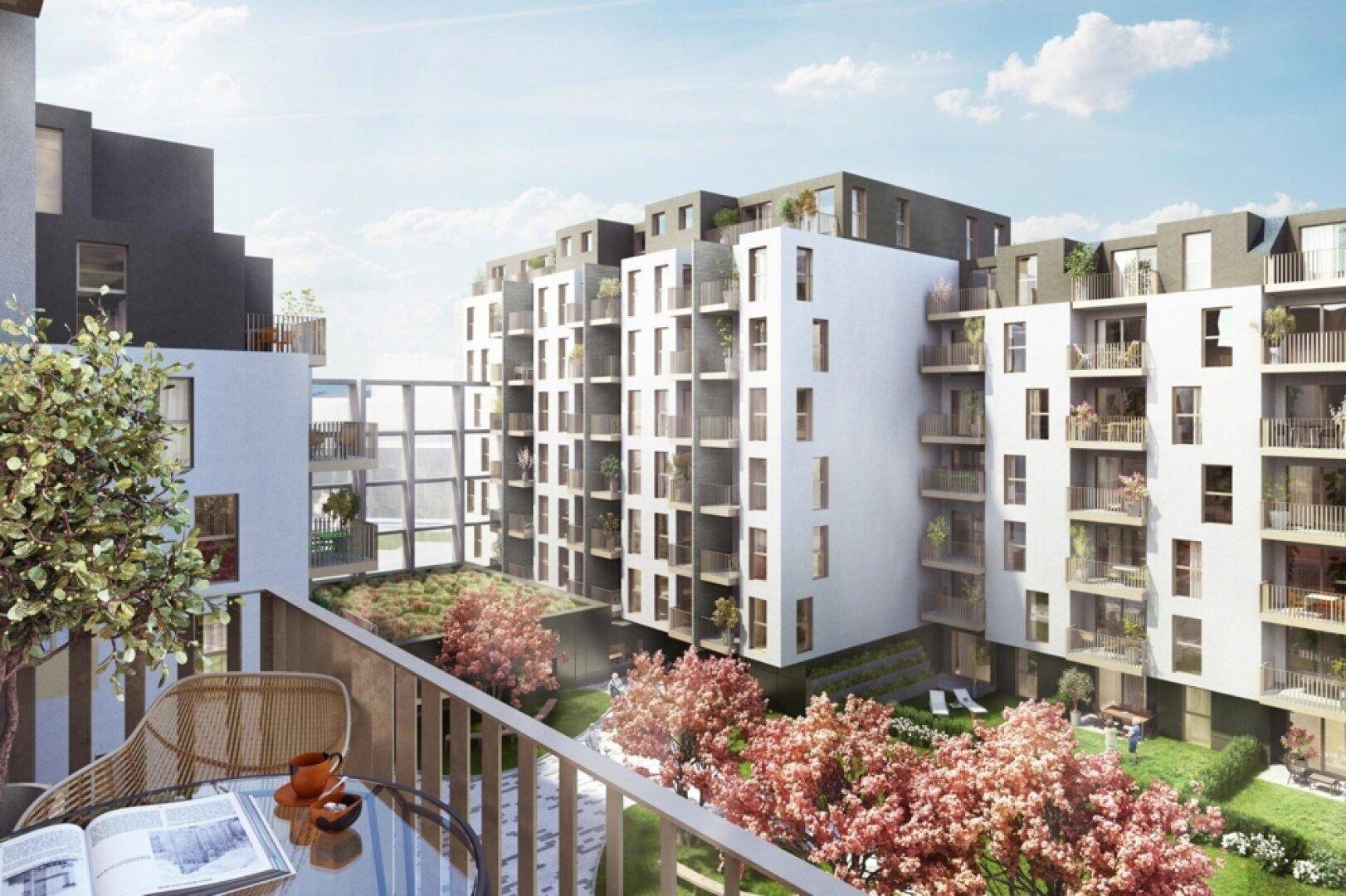 Blick von einem Balkon auf den begrünten Innenhof mit Sitzgelegenheiten und blühenden Bäumen.