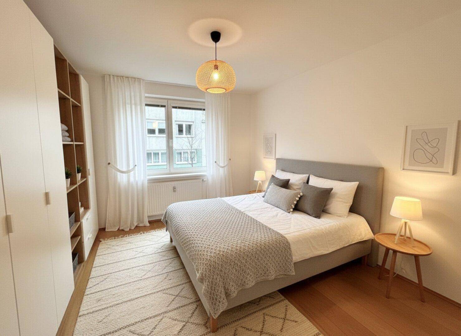 Gemütliches Schlafzimmer mit Doppelbett, Holzparkett und Blick auf die umliegenden Gebäude.