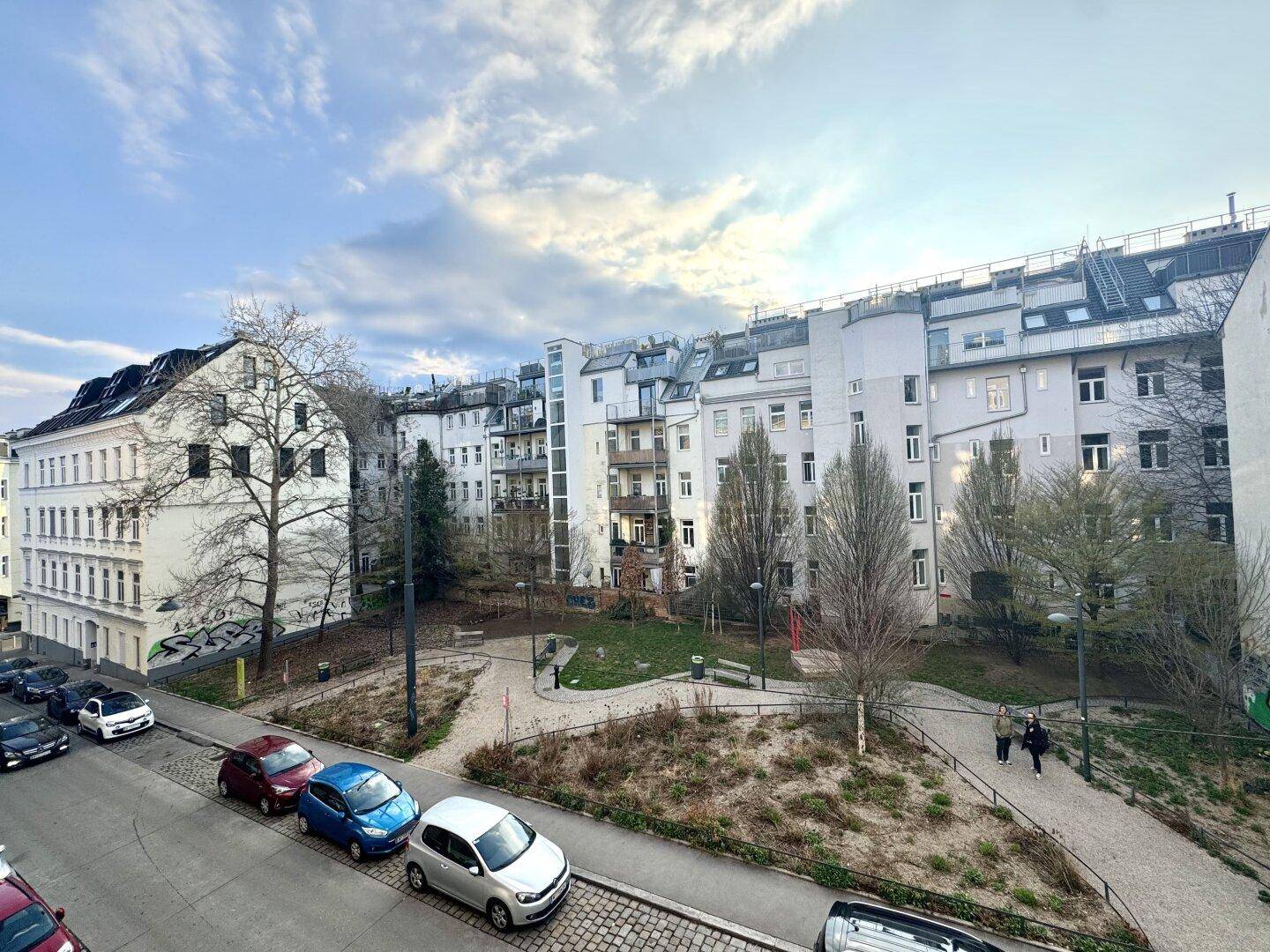 Blick auf eine Wohngegend mit mehreren Gebäuden, einer Straße und einer Grünfläche mit Bäumen.