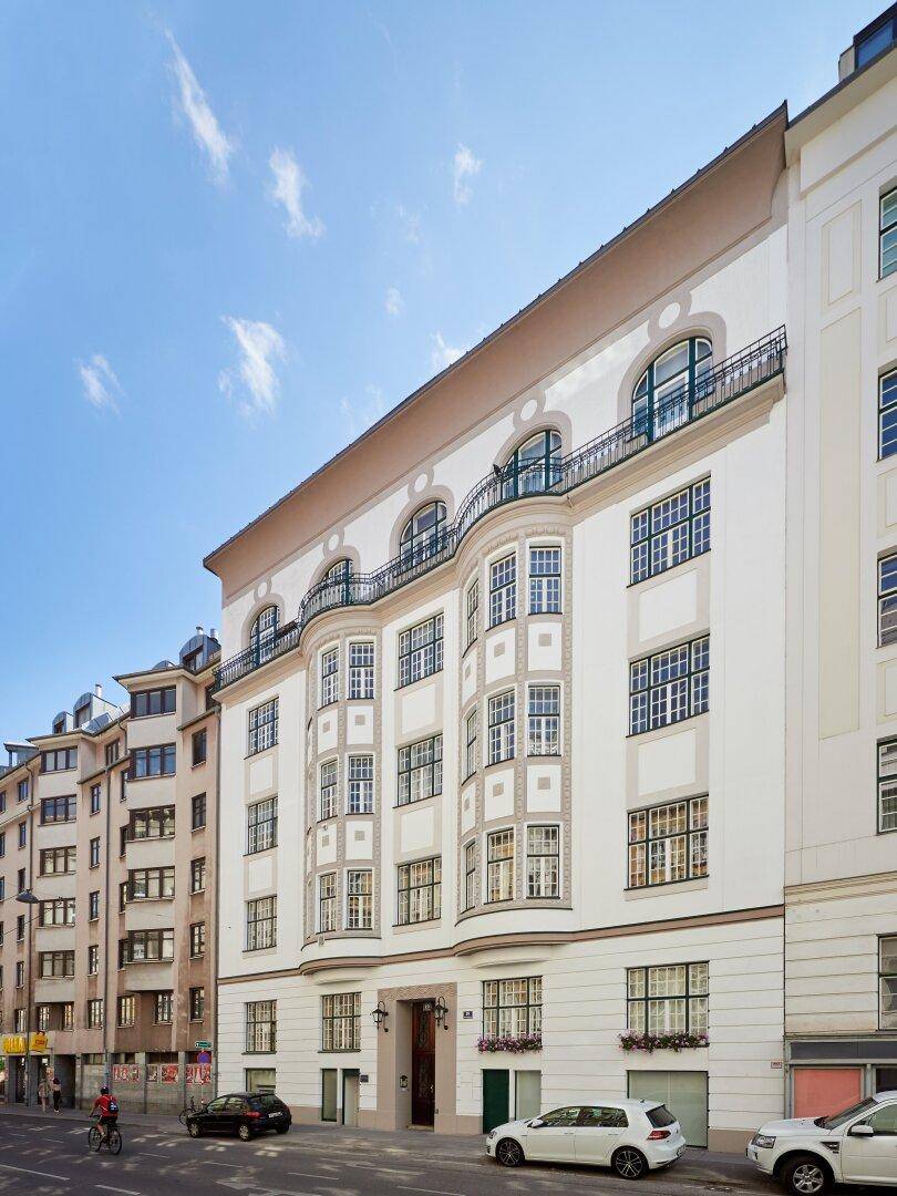 Historisches Wohngebäude mit eleganter Fassade, Erkern und Balkonen an einer Stadtstraße.