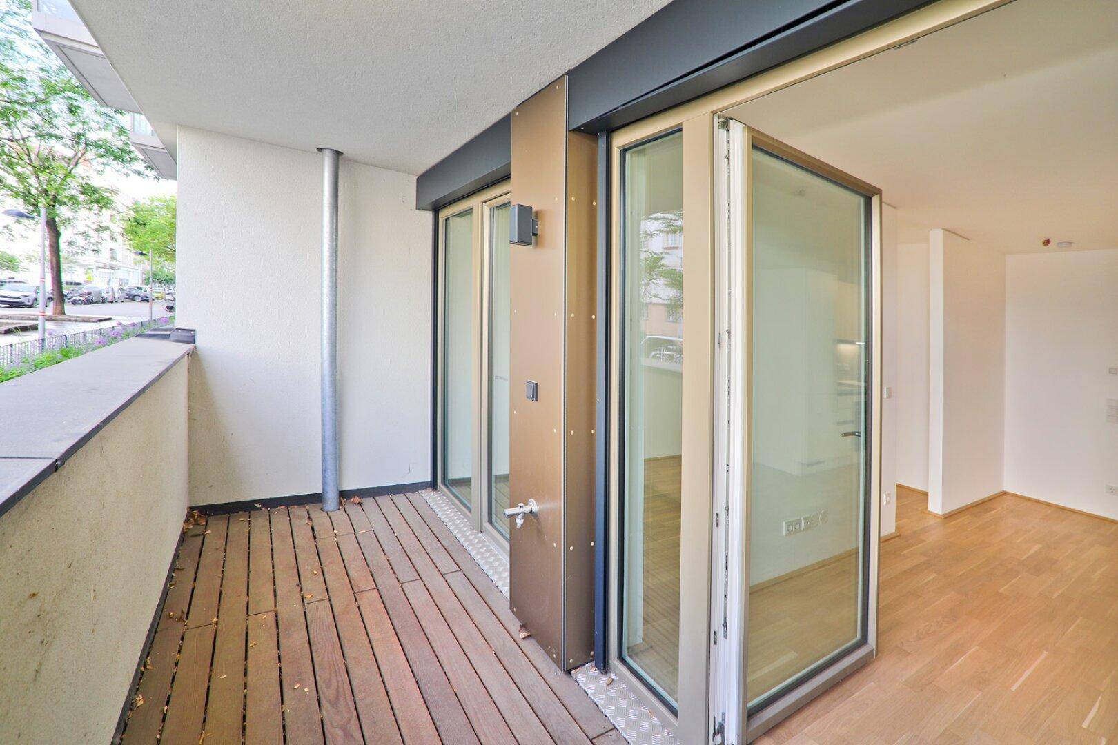 Moderner Balkon mit Holzboden und faltbaren Glasfenstern zum Innenraum.