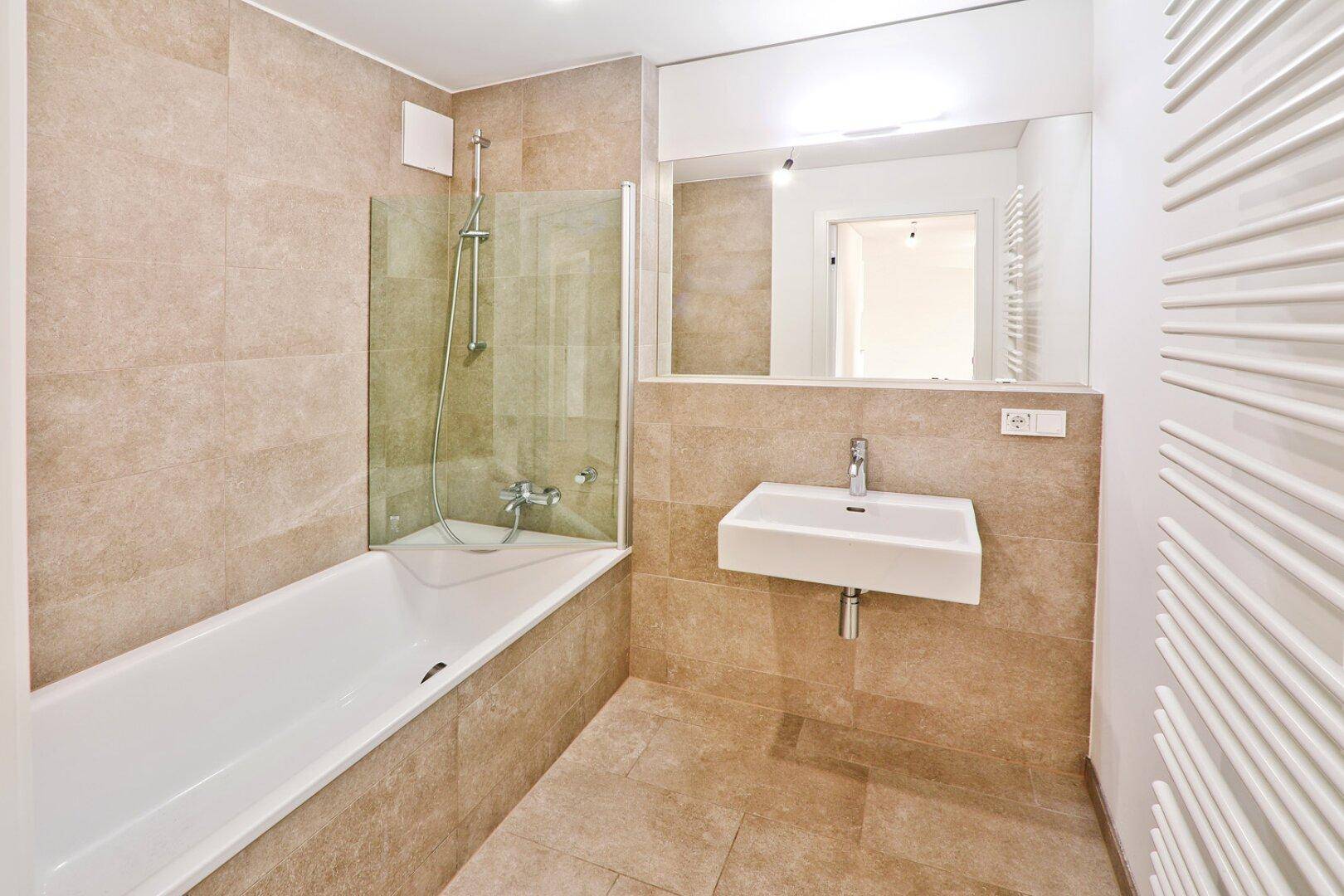 Modernes Badezimmer mit Badewanne, Dusche, Waschbecken und beheiztem Handtuchhalter.