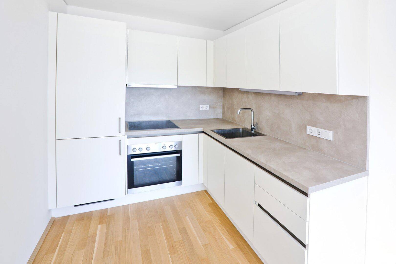 Moderne Einbauküche mit weißen Fronten, Induktionskochfeld und integriertem Backofen.