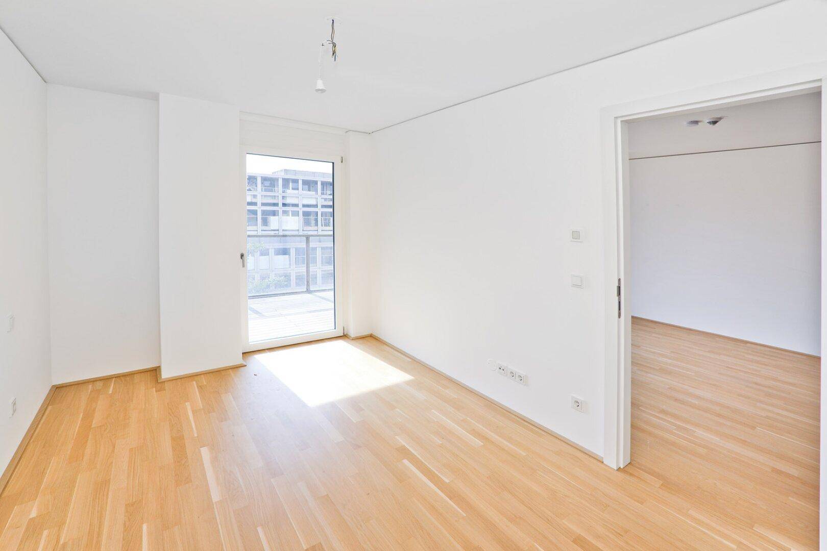 Helles Schlafzimmer mit Parkettboden und direktem Zugang zu einem Außenbereich.