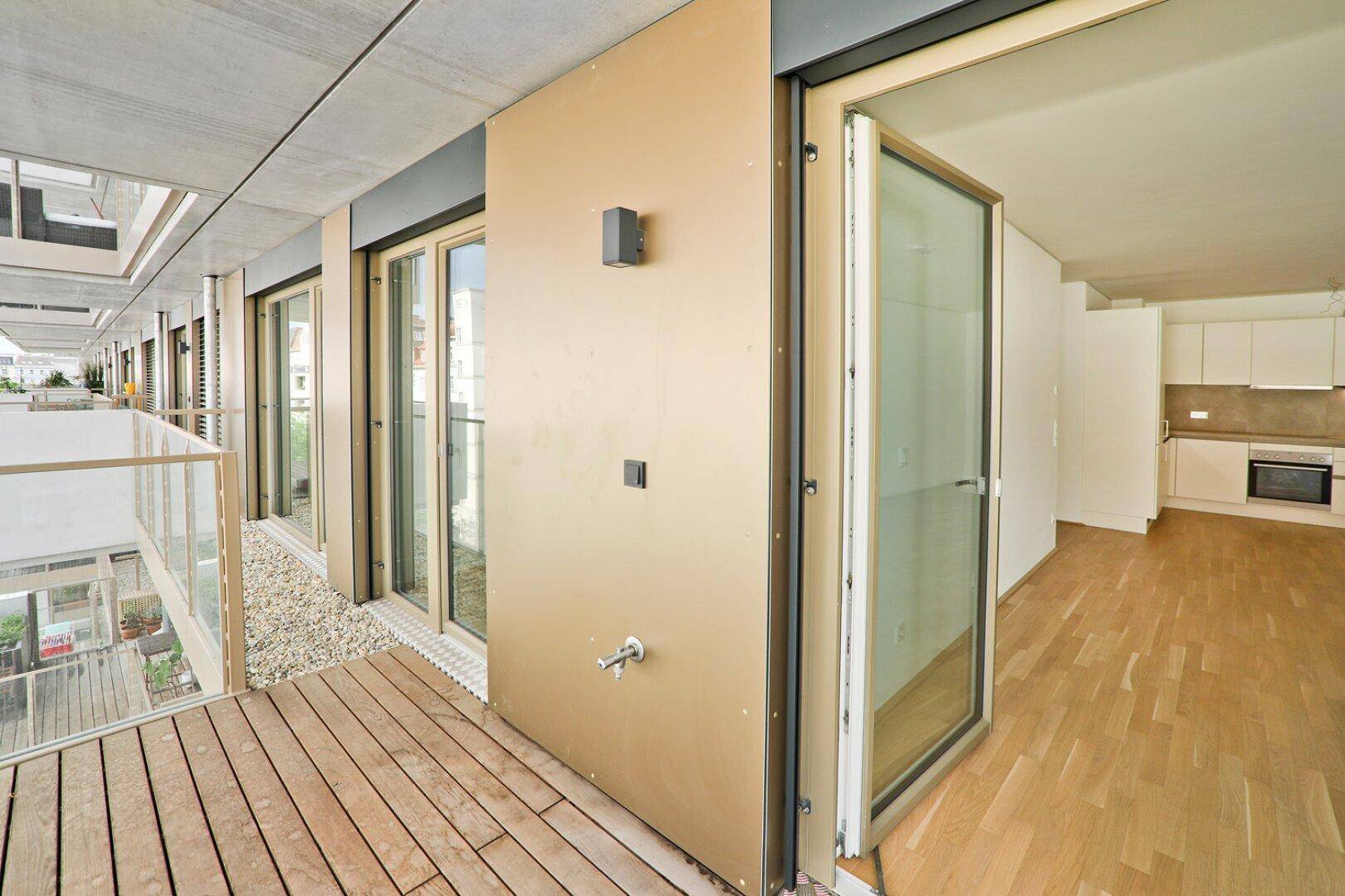 Blick vom Balkon in den offenen Wohn-Essbereich mit moderner Küche und Parkettboden.