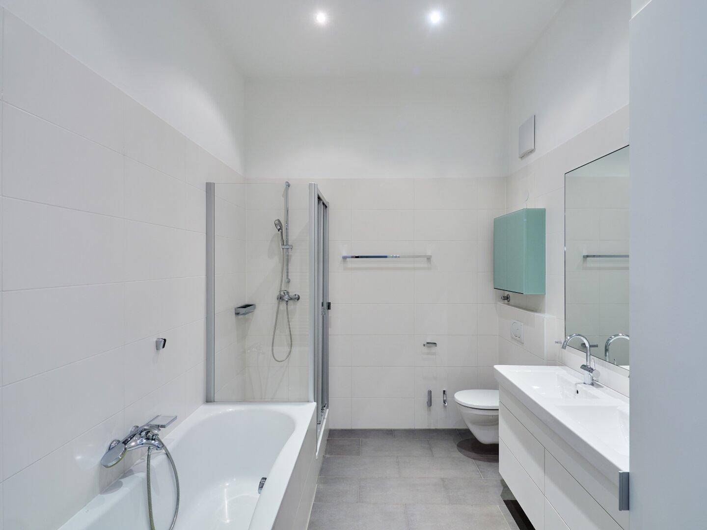 Modernes Badezimmer mit weißen Fliesen, Badewanne, Dusche und einem Waschbecken.