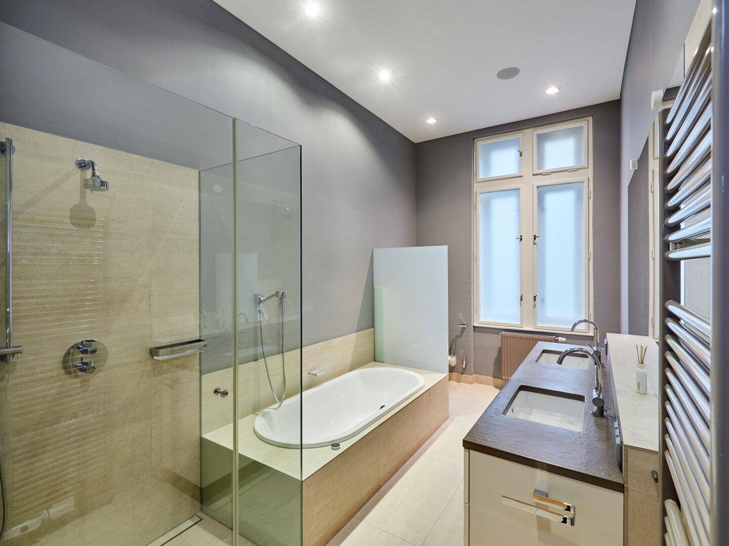 Modernes Badezimmer mit großer Dusche, Badewanne, Doppelwaschbecken und Fenster.
