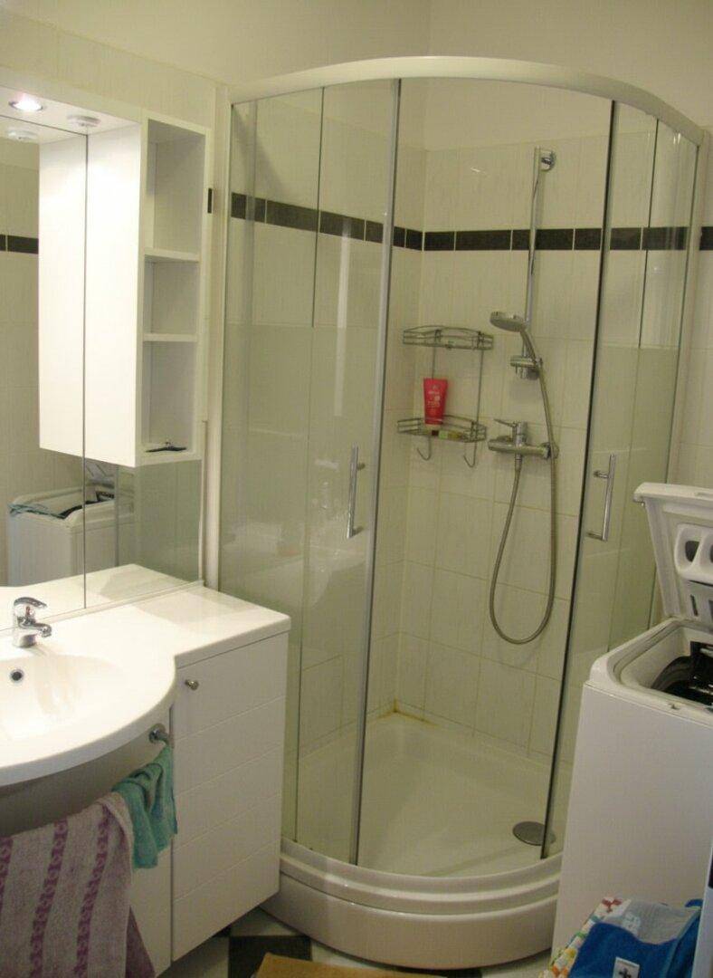 Badezimmer mit Duschkabine, Waschbecken mit Unterschrank und einer Waschmaschine.